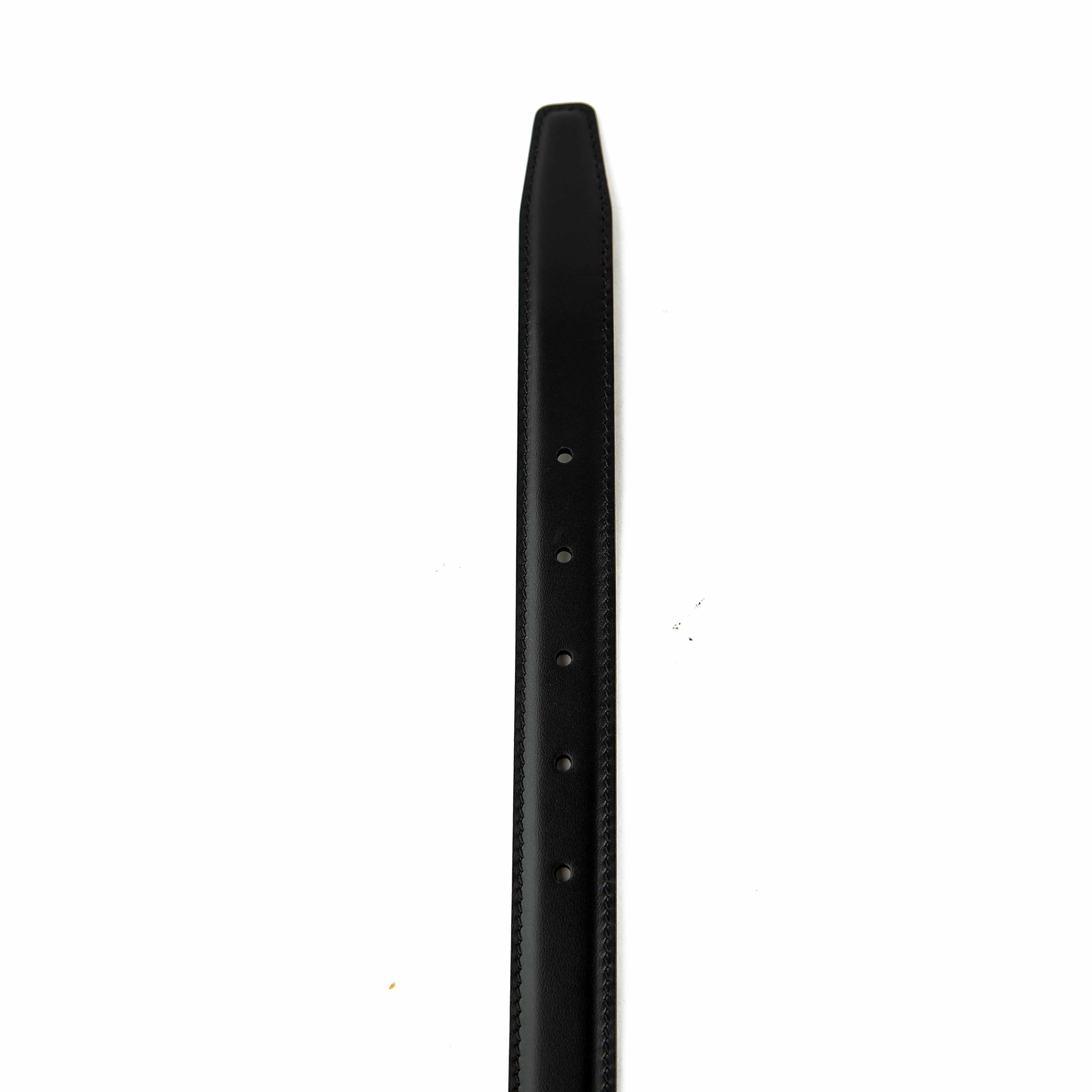 This elegant accessory is a masterclass in understated luxury, featuring a smooth, semi-matte black calfskin leather strap.