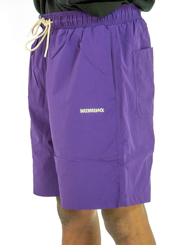 Purple nylon swim shorts with elastic waistband and drawstring closure, shown.