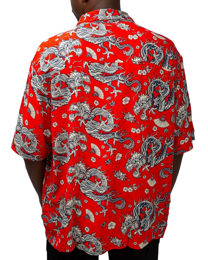 Men's white short sleeve button-down shirt with artistic tropical print featuring peacocks, abstract designs, and botanical elements.