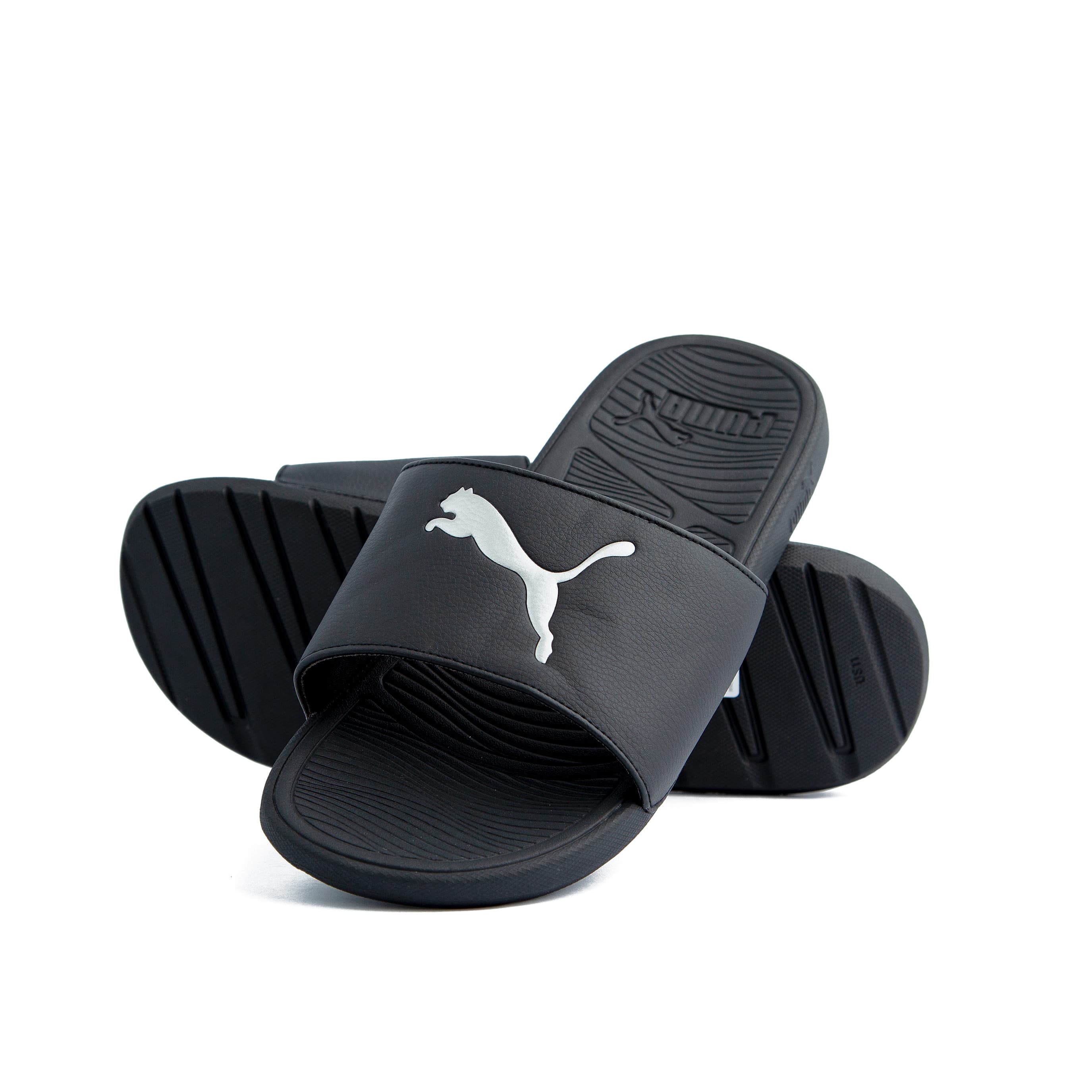 Black Puma slide sandals with white logo, unisex design, durable strap, and comfortable textured footbed for casual wear and relaxation.