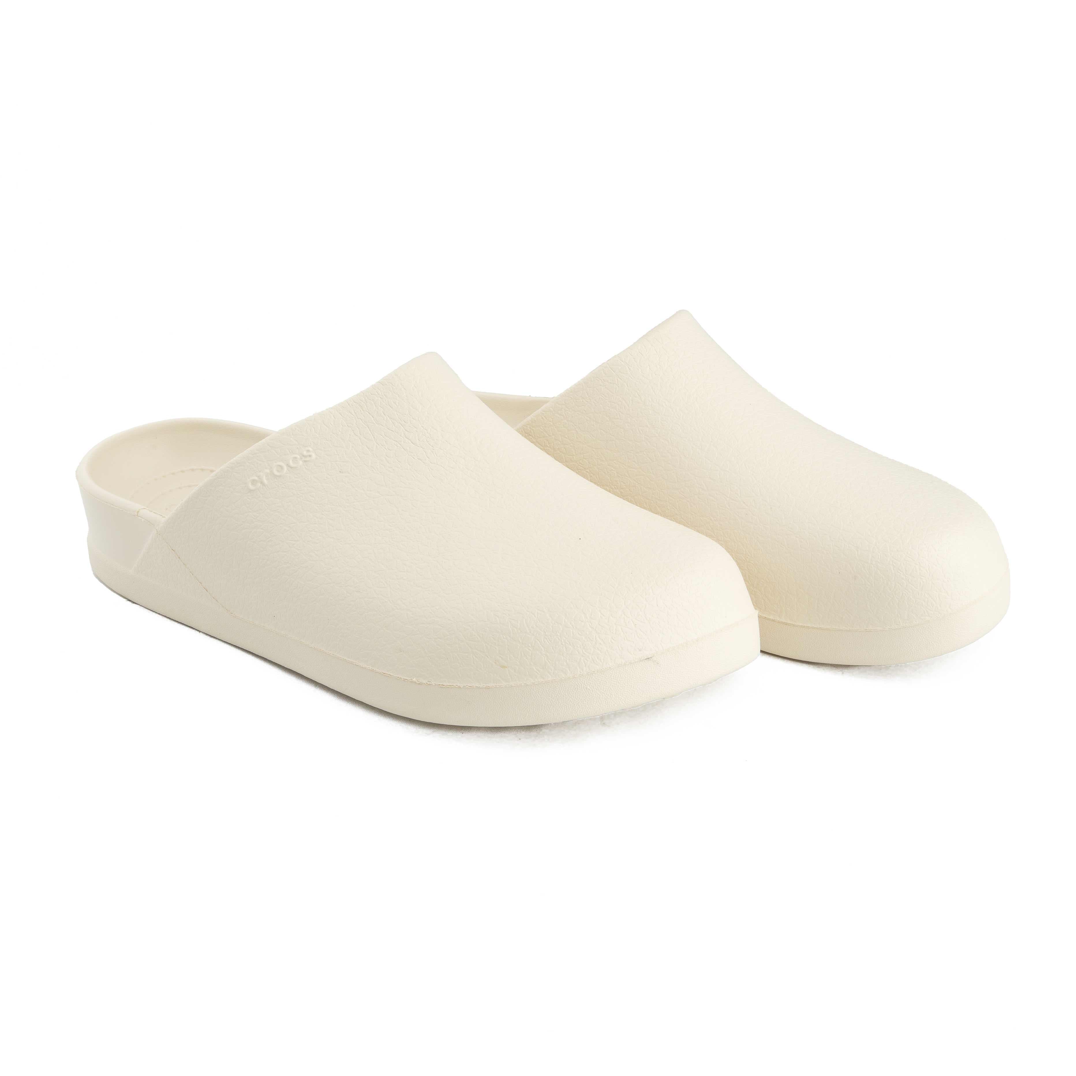 This is a pair of closed-toe, unvented clogs from the Crocs brand, presented in a soft, off-white color. 