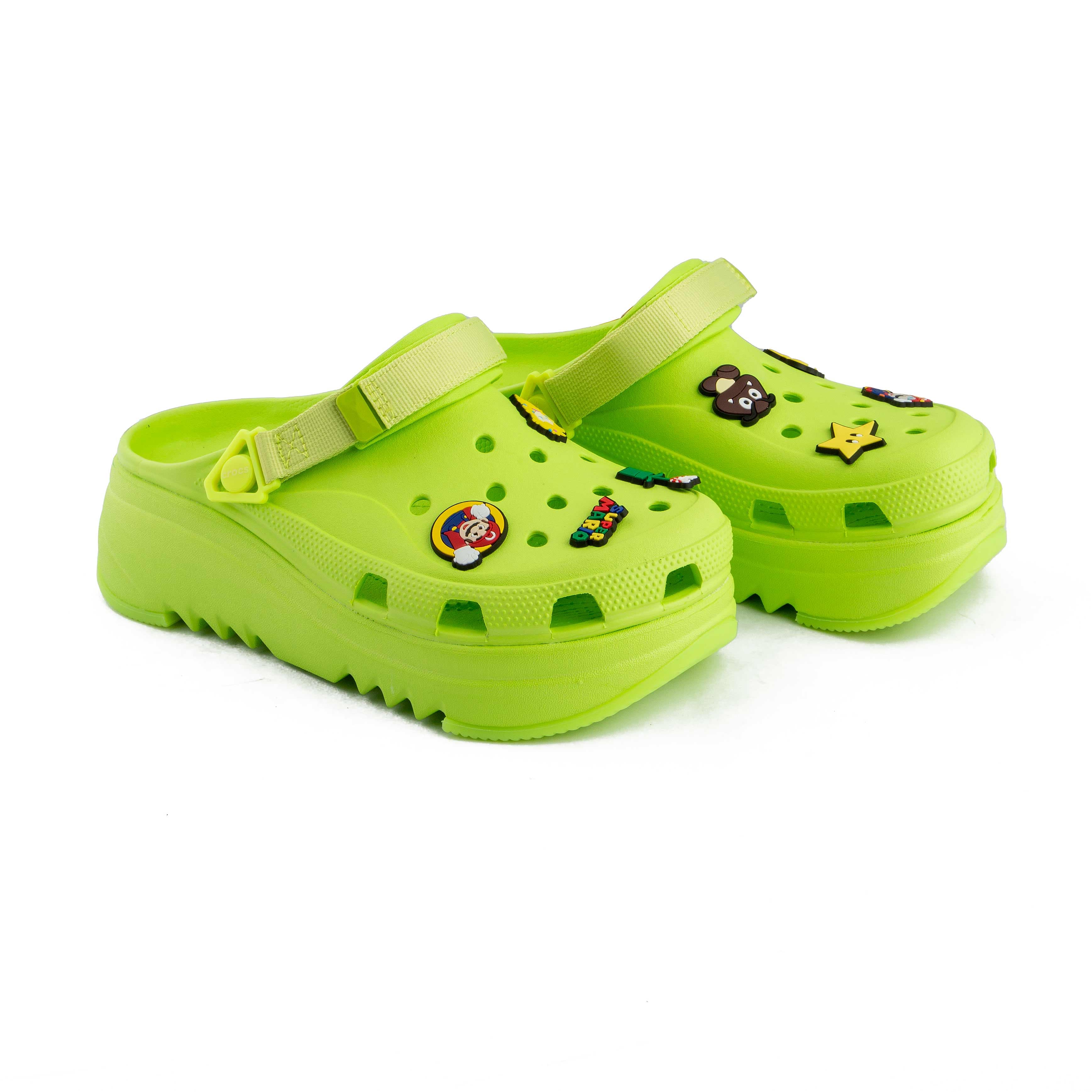 Lime green platform clogs with assorted colorful decorative charms, side view.
