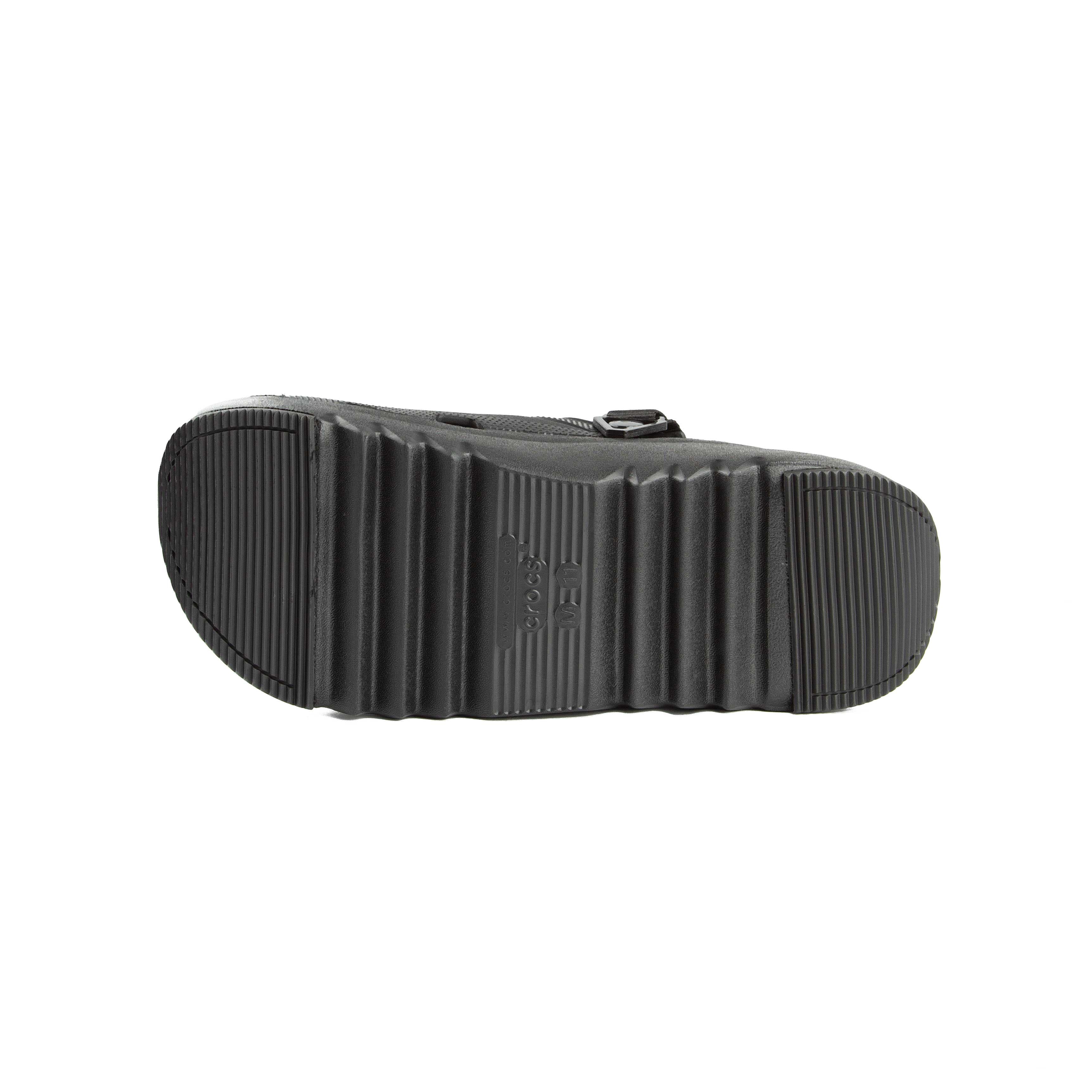Black platform clogs with assorted colorful decorative charms, side view.