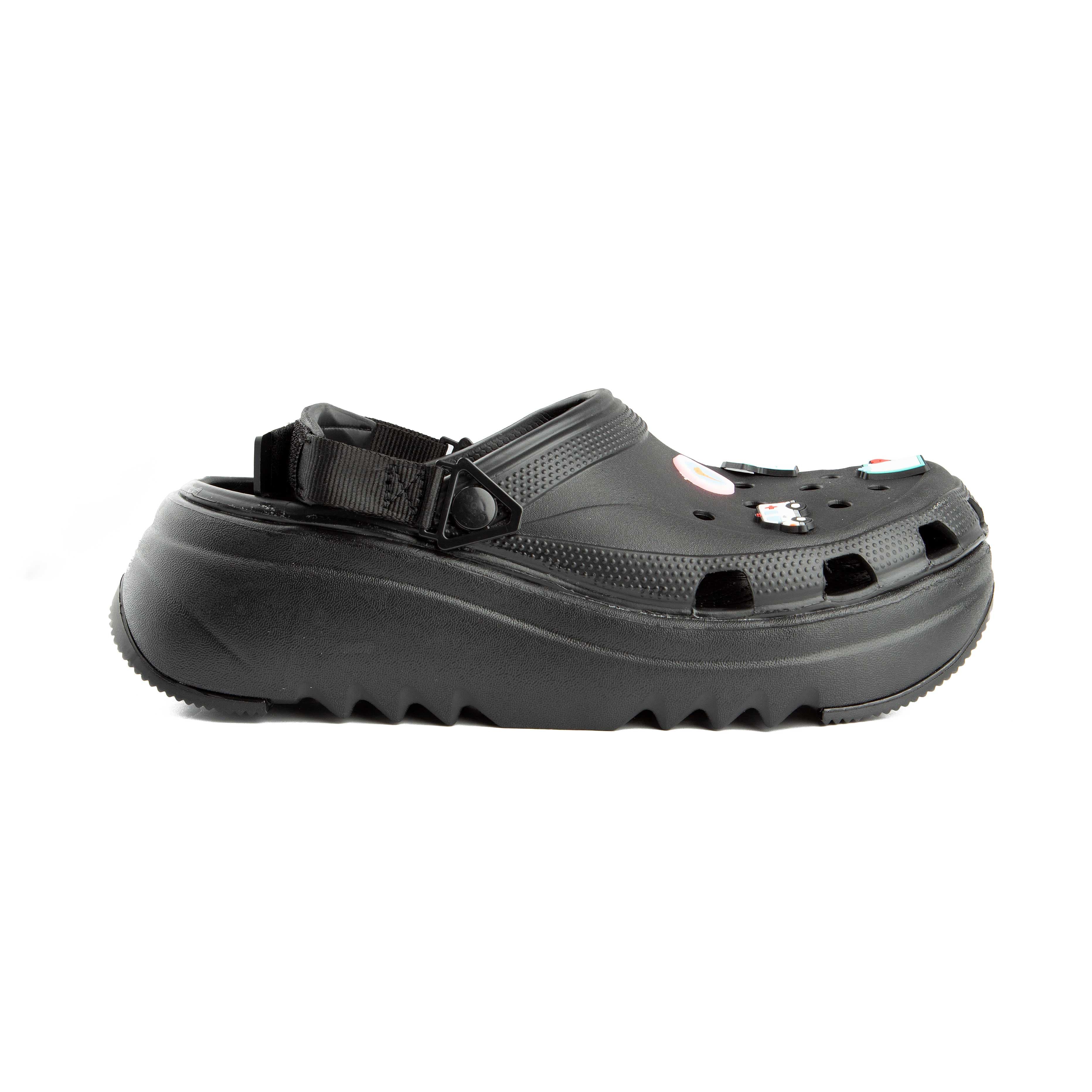 Black platform clogs with assorted colorful decorative charms, side view.