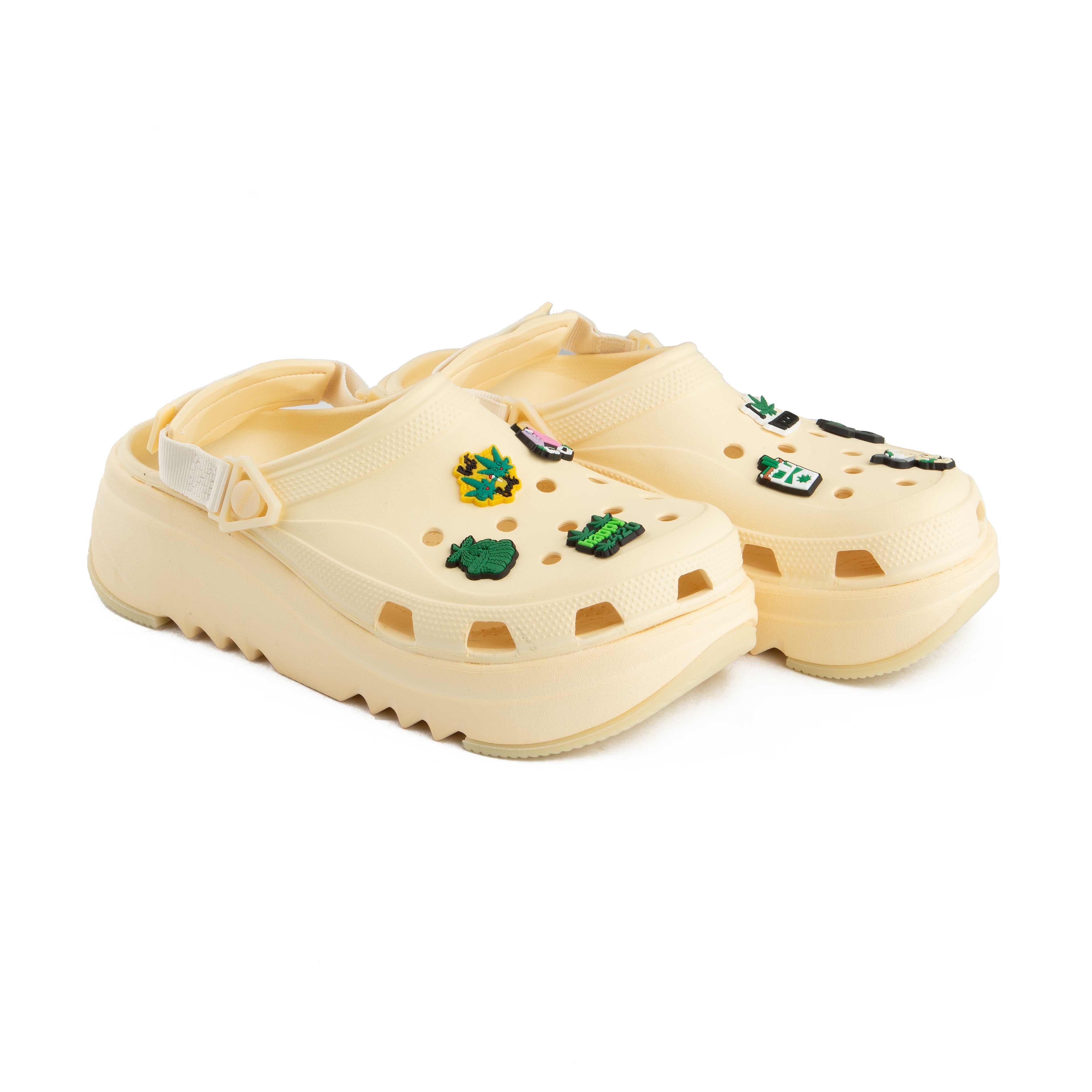 Cream platform clogs with assorted nature-themed decorative charms, side view.