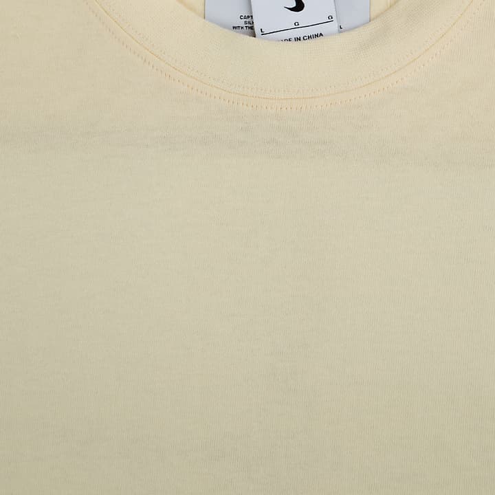 A plain cream-colored Nike t-shirt with a minimalist, clean design.