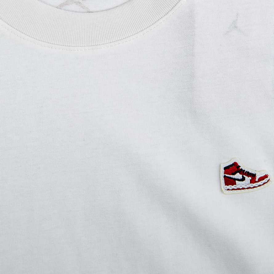 A white Jordan Flight Heritage T-shirt with a small embroidered winged shoe logo on the chest.