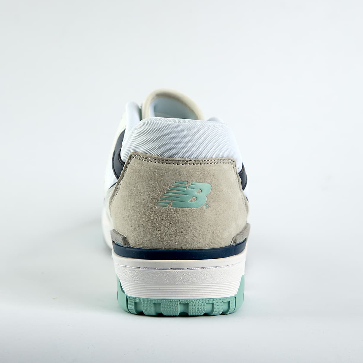New Balance 550 sneakers in off-white with mint green, taupe, and gray accents. A retro low-top shoe for men and women.