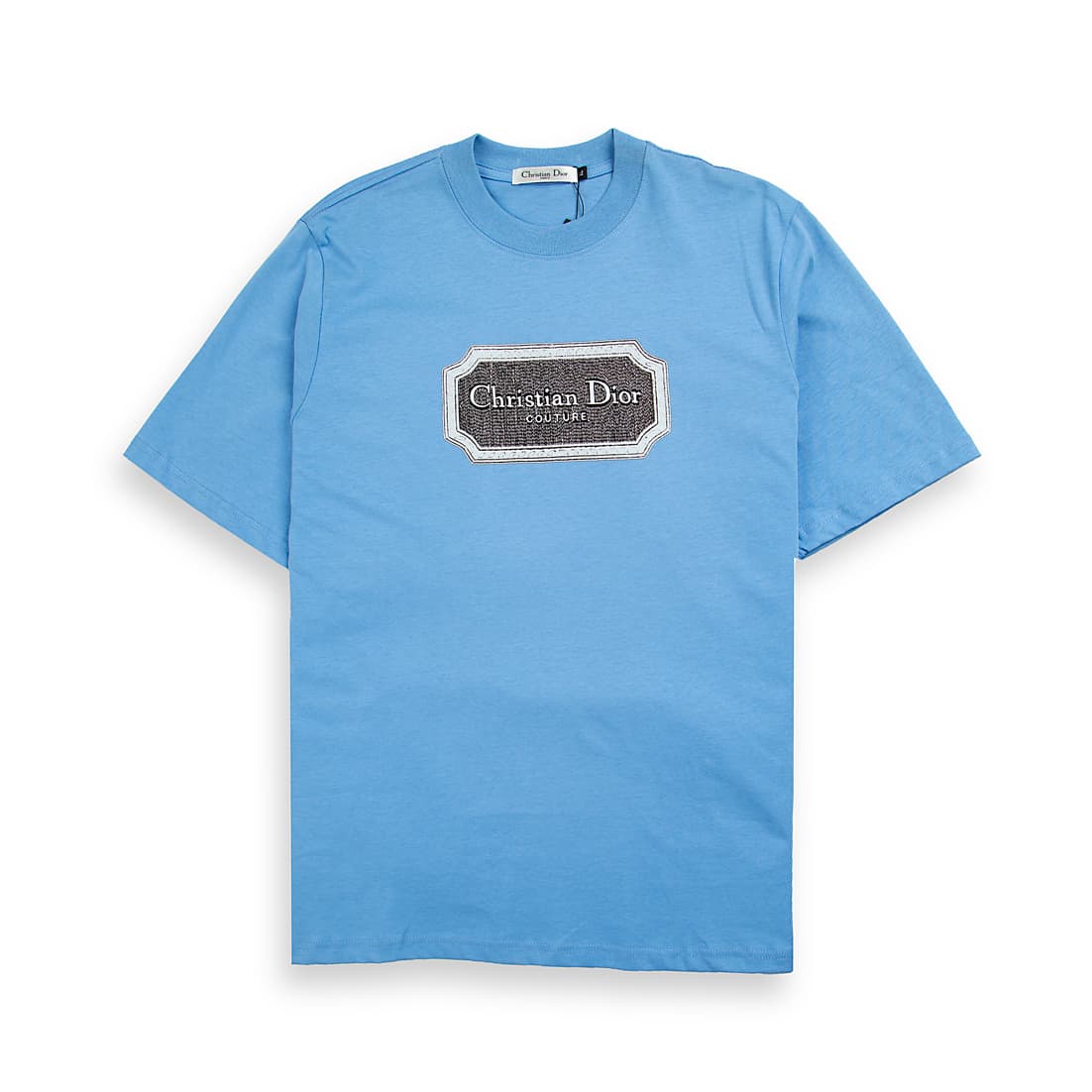 Light blue Christian Dior t-shirt with brown couture patch logo graphic on chest, luxury unisex style.