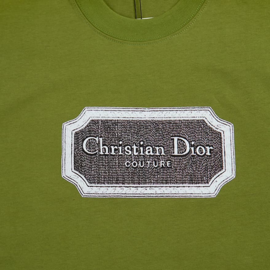 Olive Green Christian Dior t-shirt with brown couture patch logo graphic on chest, luxury unisex style.