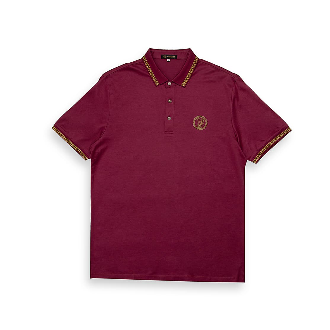 Maroon Versace polo shirt with gold Greek Key trim on collar/cuffs and embroidered Medusa crest, luxury short sleeve.