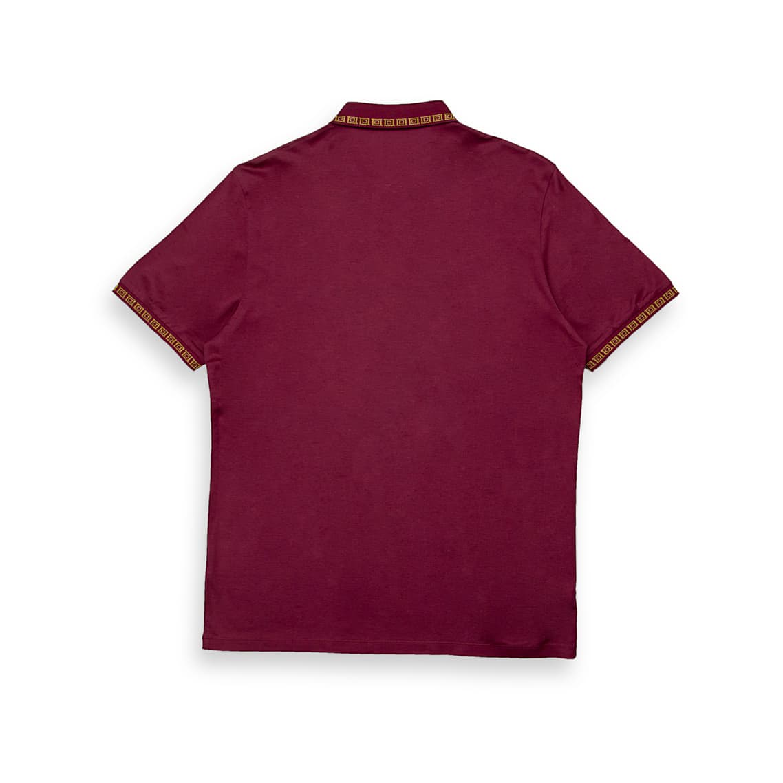 Maroon Versace polo shirt with gold Greek Key trim on collar/cuffs and embroidered Medusa crest, luxury short sleeve.