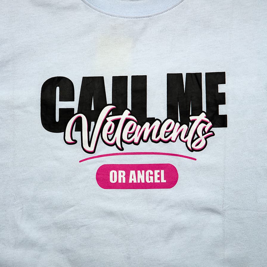 This is a white, short-sleeve crew-neck t-shirt featuring a bold, playful, and high-fashion inspired graphic slogan.