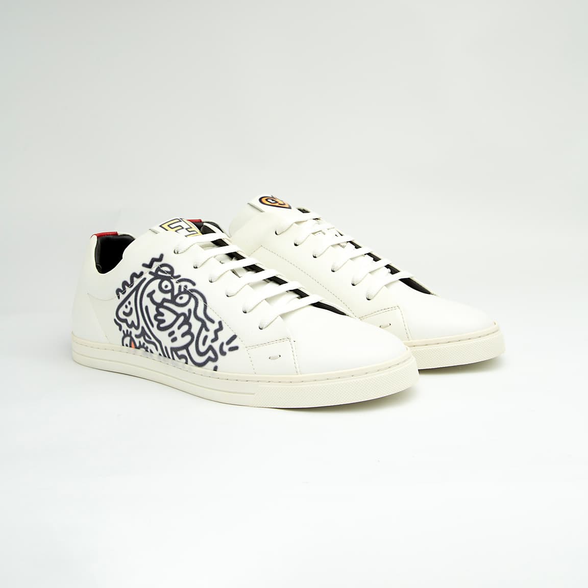 The White Tiger Skate Low is a clean, modern, low-top trainer with a luxury streetwear edge. It is crafted from smooth, premium white leather and features a distinctive black and white graphic drawing on the side panel, resembling a stylized tiger or abstract artwork.