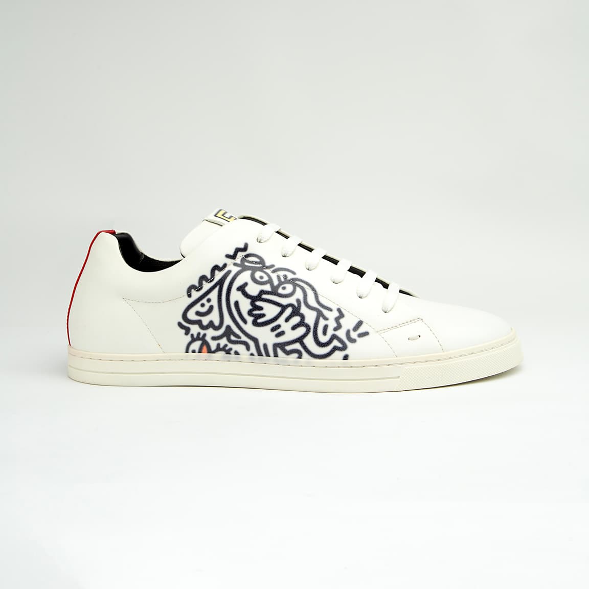 The White Tiger Skate Low is a clean, modern, low-top trainer with a luxury streetwear edge. It is crafted from smooth, premium white leather and features a distinctive black and white graphic drawing on the side panel, resembling a stylized tiger or abstract artwork.