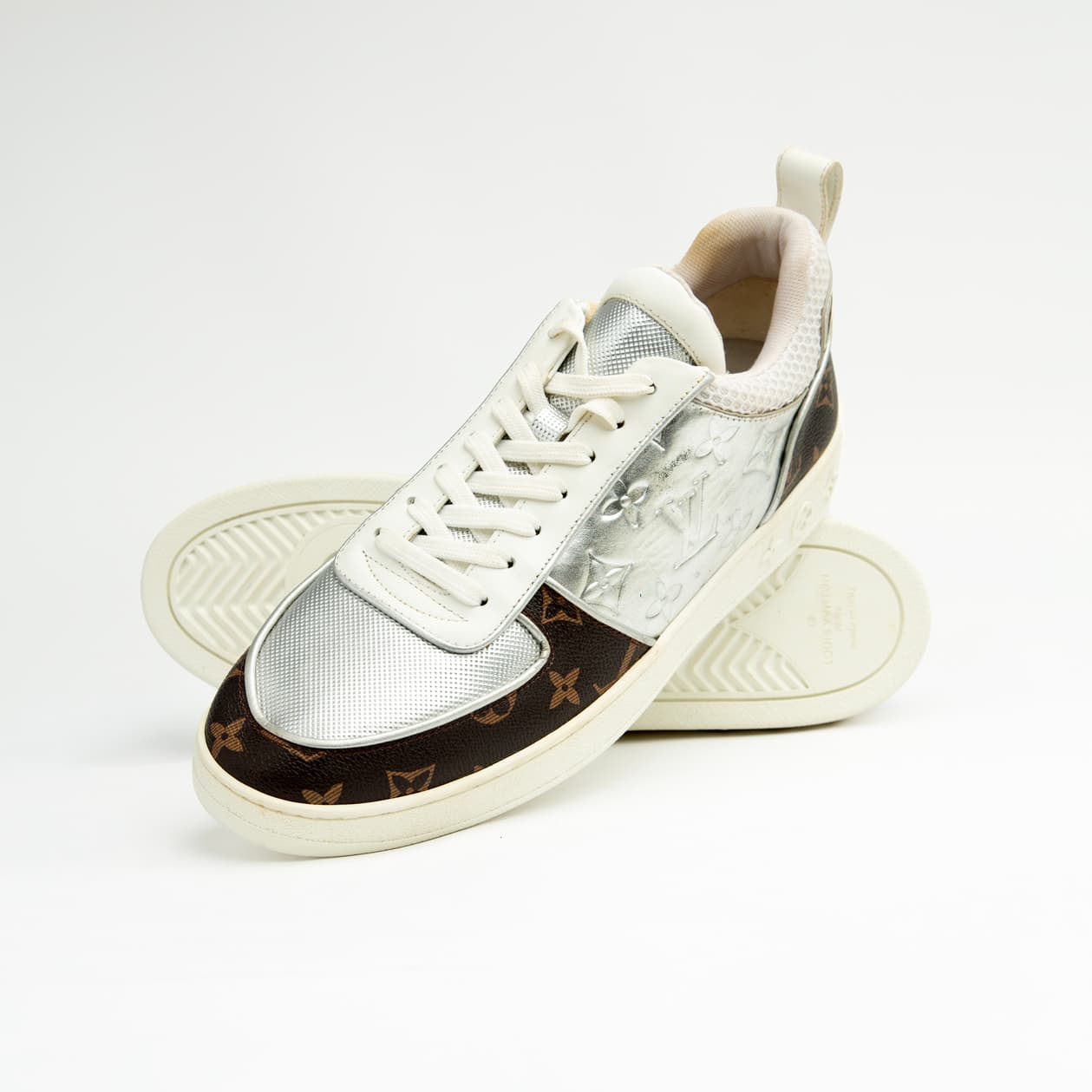 Dual-tone brown and silver unisex monogram embossed leather sneakers with classic design and comfortable sole.
