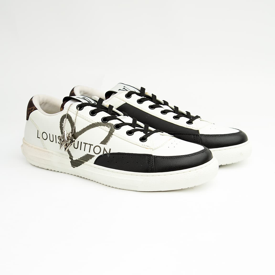 Louis Vuitton Black Heart unisex sneakers in white and black leather with LV heart motif and logo charm — luxury designer footwear.