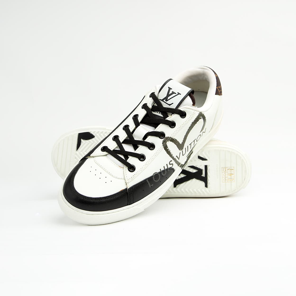 Louis Vuitton Black Heart unisex sneakers in white and black leather with LV heart motif and logo charm — luxury designer footwear.