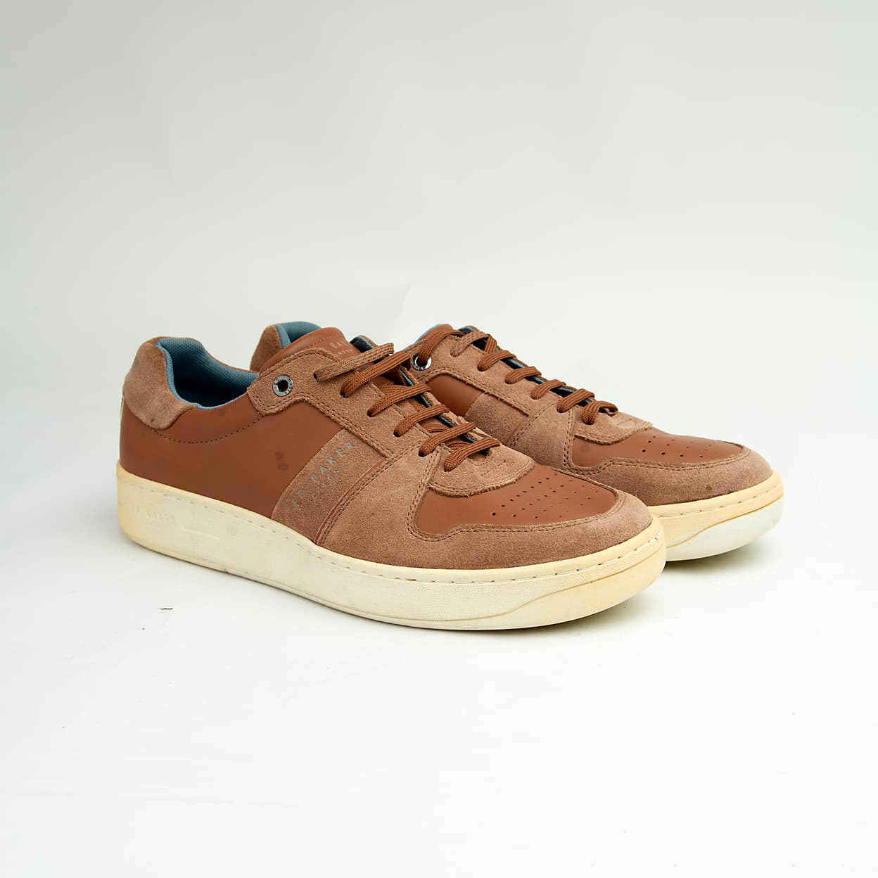 These versatile sneakers are crafted from a sophisticated mix of materials, featuring smooth brown leather panels complemented by textural suede accents in a matching tonal palette.