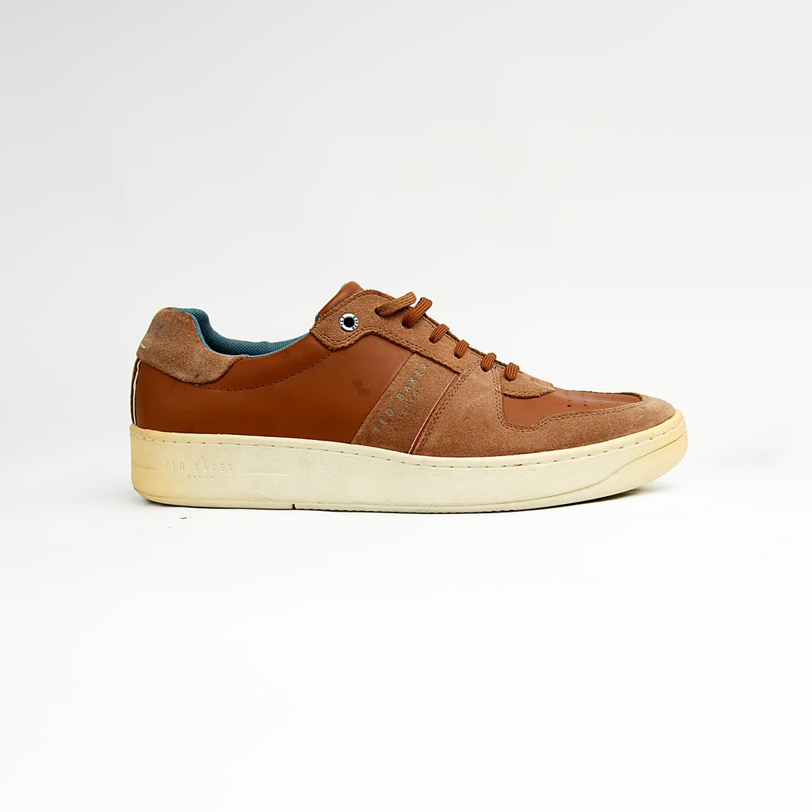 These versatile sneakers are crafted from a sophisticated mix of materials, featuring smooth brown leather panels complemented by textural suede accents in a matching tonal palette.