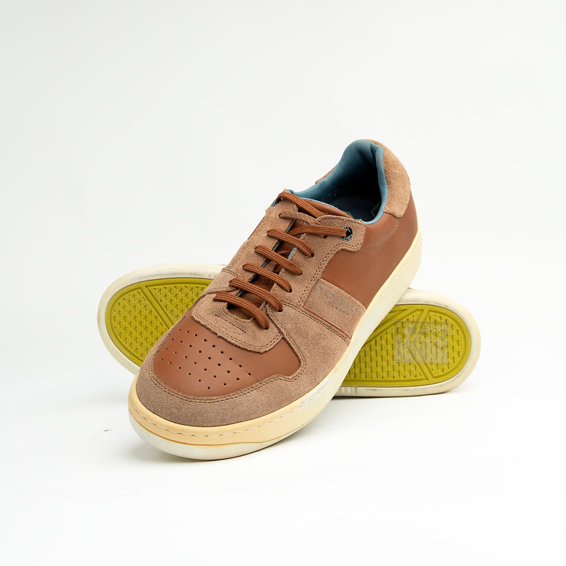 These versatile sneakers are crafted from a sophisticated mix of materials, featuring smooth brown leather panels complemented by textural suede accents in a matching tonal palette.