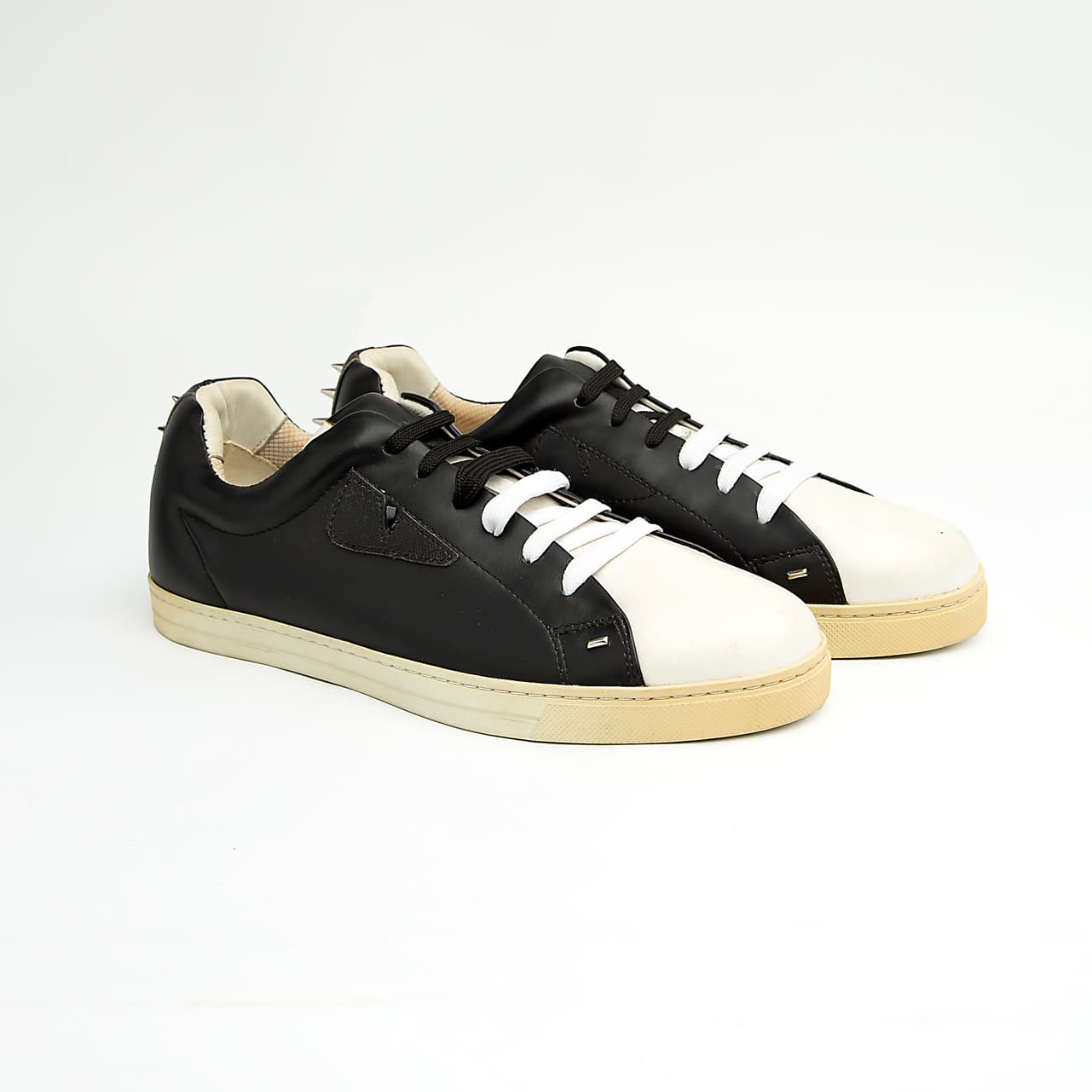 These sleek, premium leather sneakers perfectly blend classic low-top styling with the brand's signature playful-yet-edgy aesthetic.
