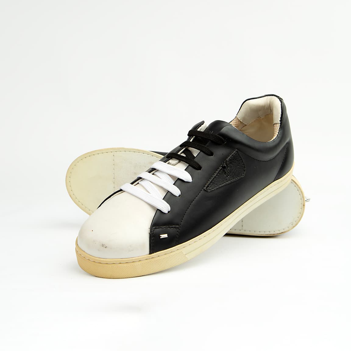 These sleek, premium leather sneakers perfectly blend classic low-top styling with the brand's signature playful-yet-edgy aesthetic.