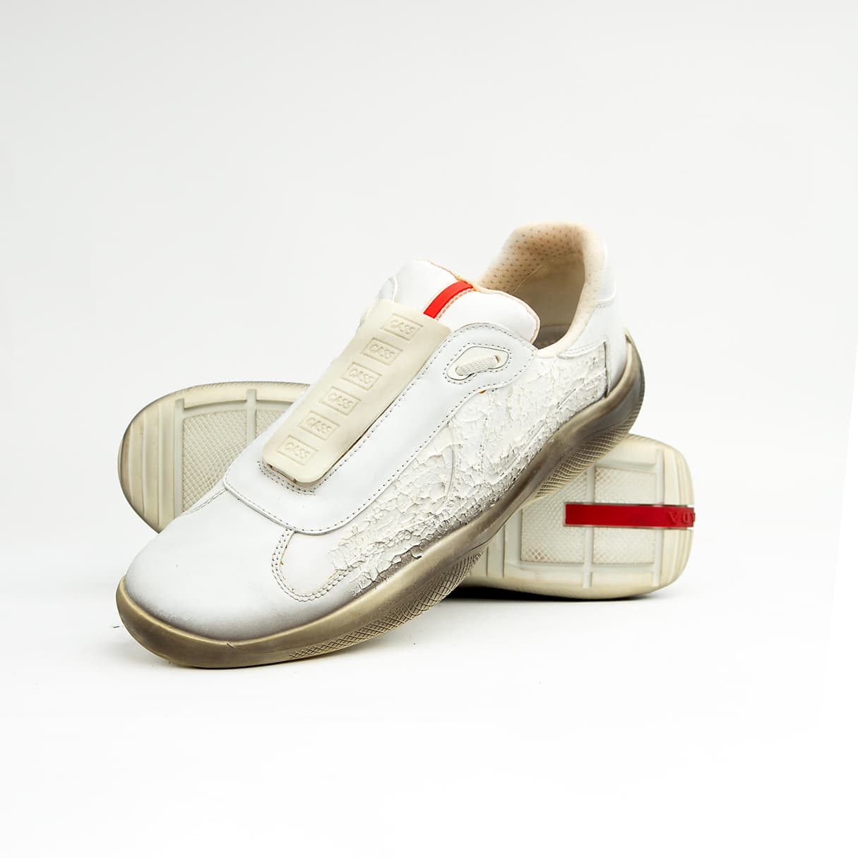 These high-fashion sneakers feature a unique white leather upper with a striking, textured cracked/distressed finish that fades dramatically into a darker, almost gradient effect at the midsole line, evoking the look of a receding glacier or ancient ice.