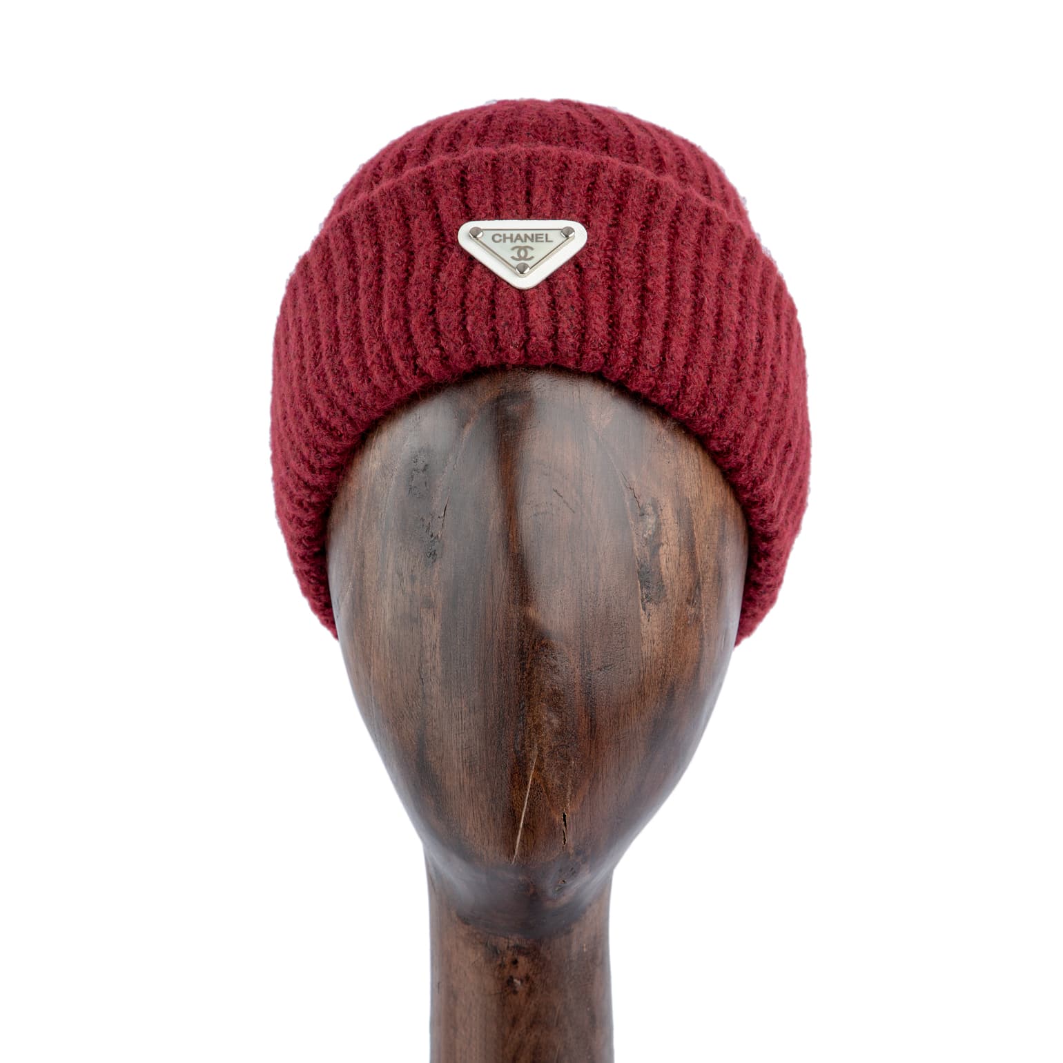 Burgundy ribbed wool beanie with silver metal emblem, perfect for winter warmth and a stylish statement.