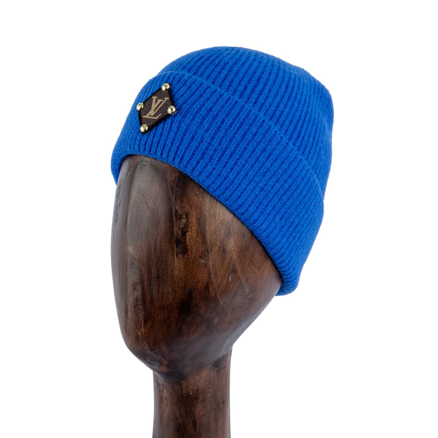 Blue knit beanie with monogram leather patch and gold studs, designed for style and warmth.