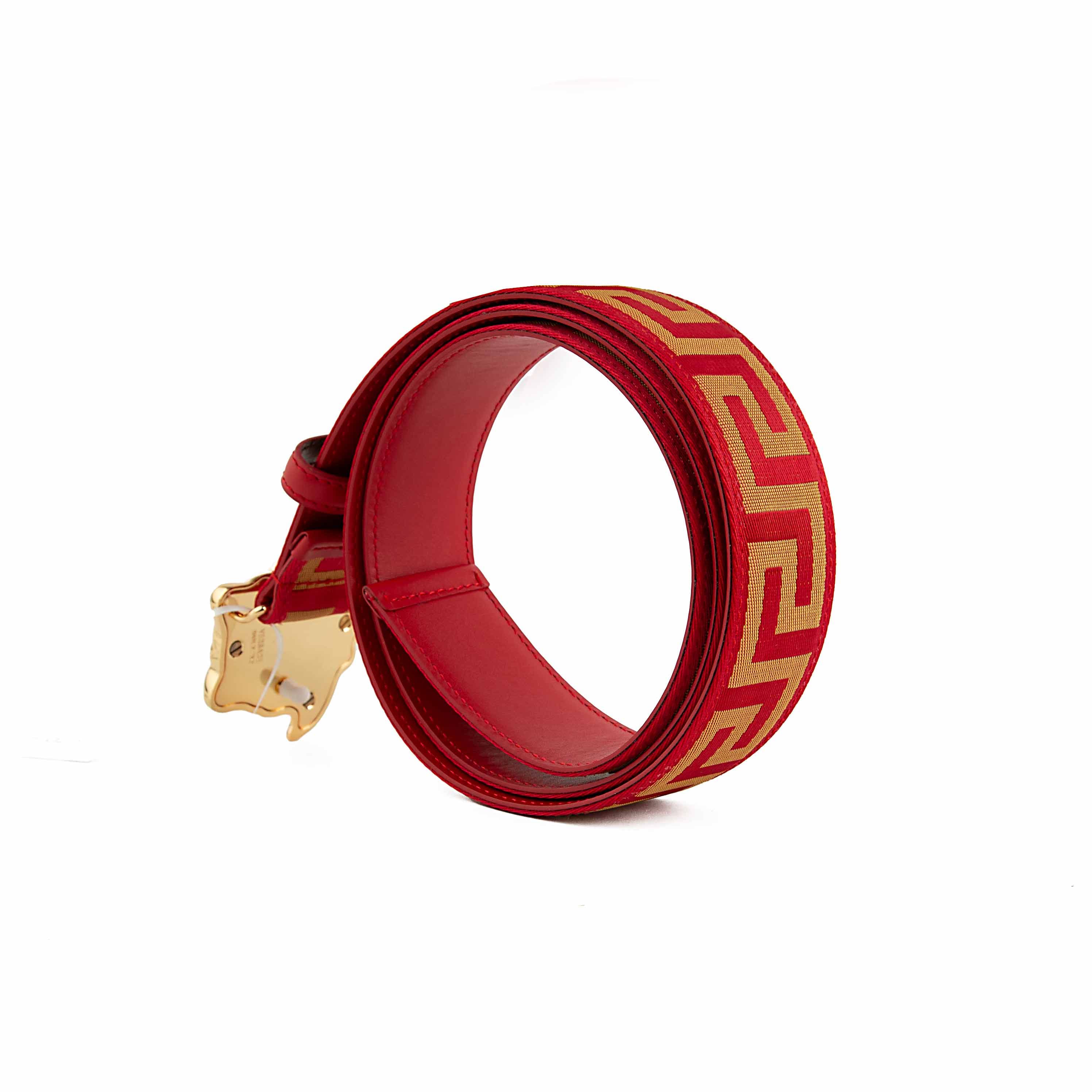 This belt is a masterclass in bold, unapologetic luxury. It features a vibrant scarlet red strap adorned with a continuous gold-tone Greca (Greek Key) motif, meticulously woven into a textured jacquard fabric.