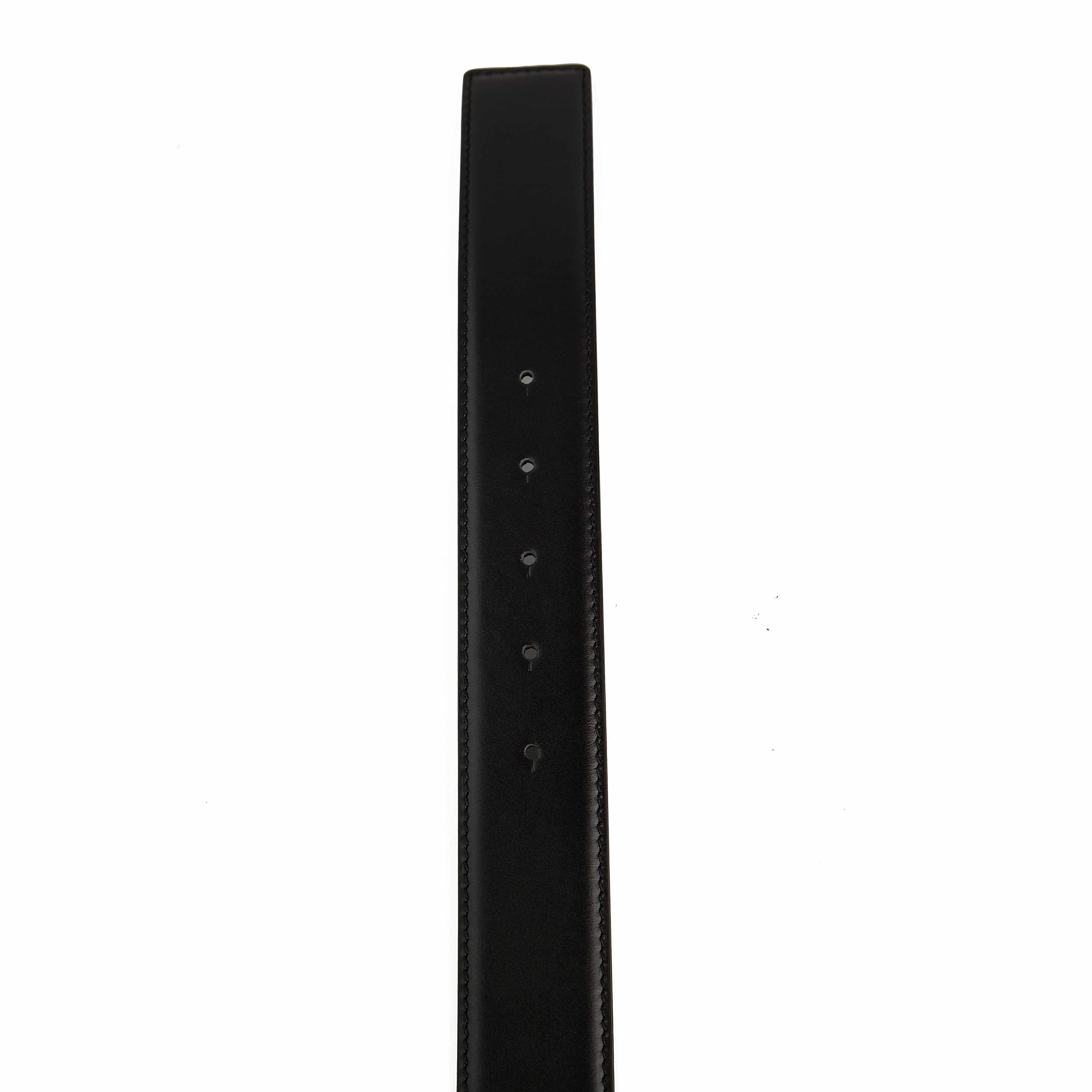 This accessory is a smooth black leather belt that serves as a bold statement piece.