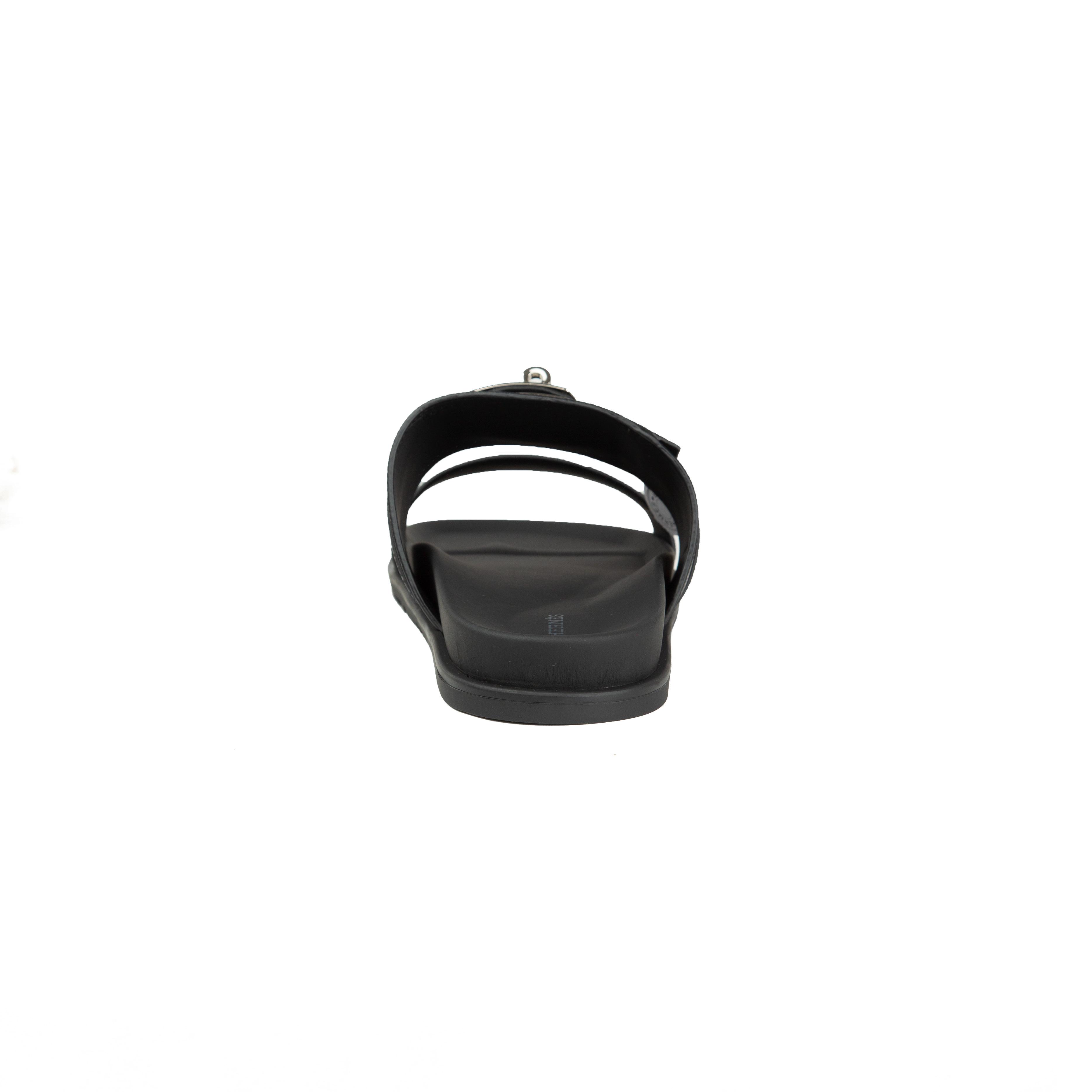Black Hermès Chypre sandals in grained Epsom leather with silver Kelly buckle on a white background.