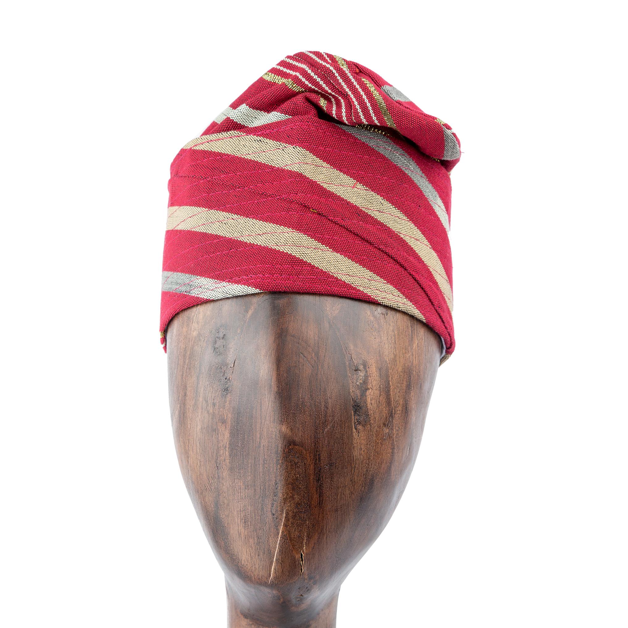 A Red and Gold Striped Yoruba Fila, meticulously folded and displayed on a wooden mannequin head.