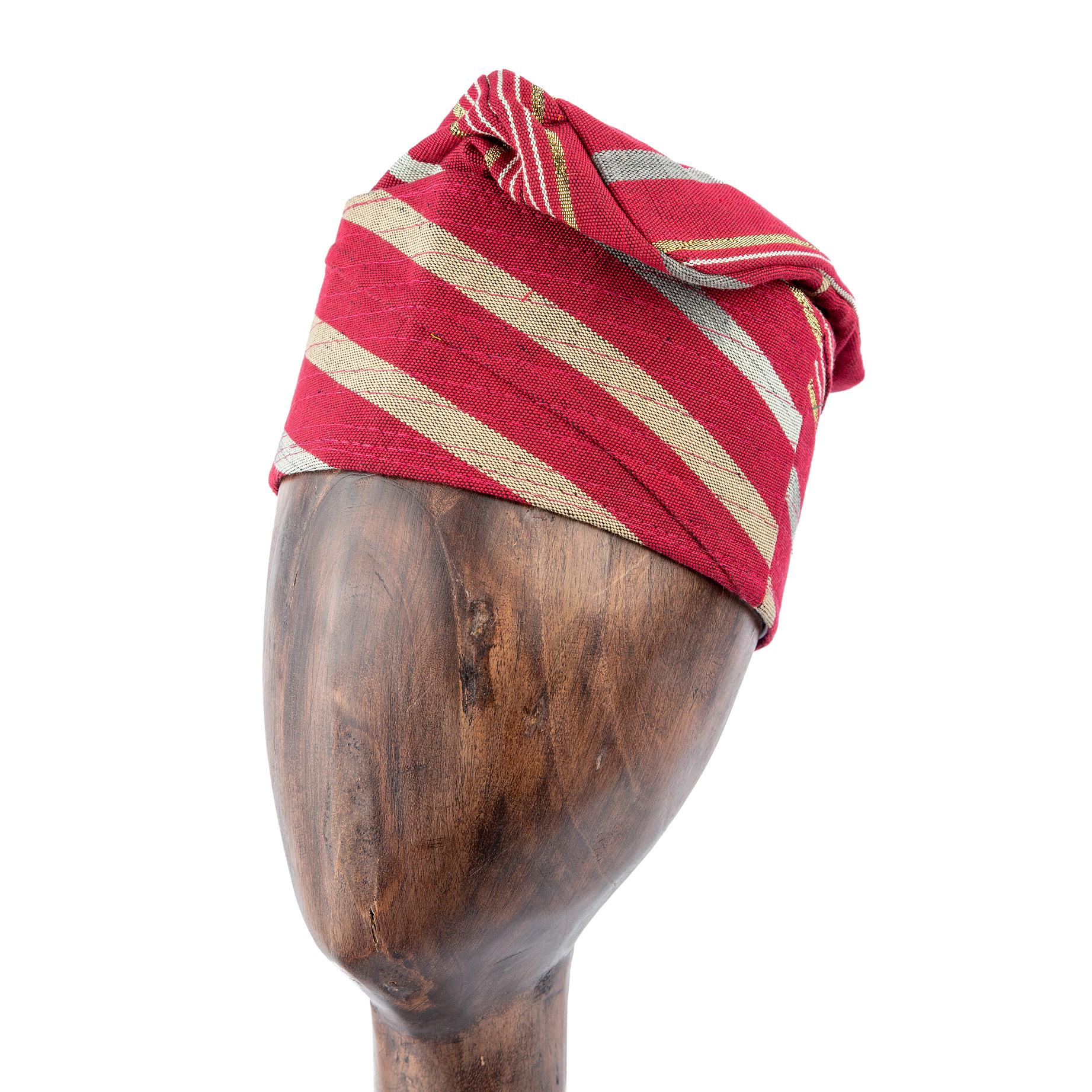 A Red and Gold Striped Yoruba Fila, meticulously folded and displayed on a wooden mannequin head.