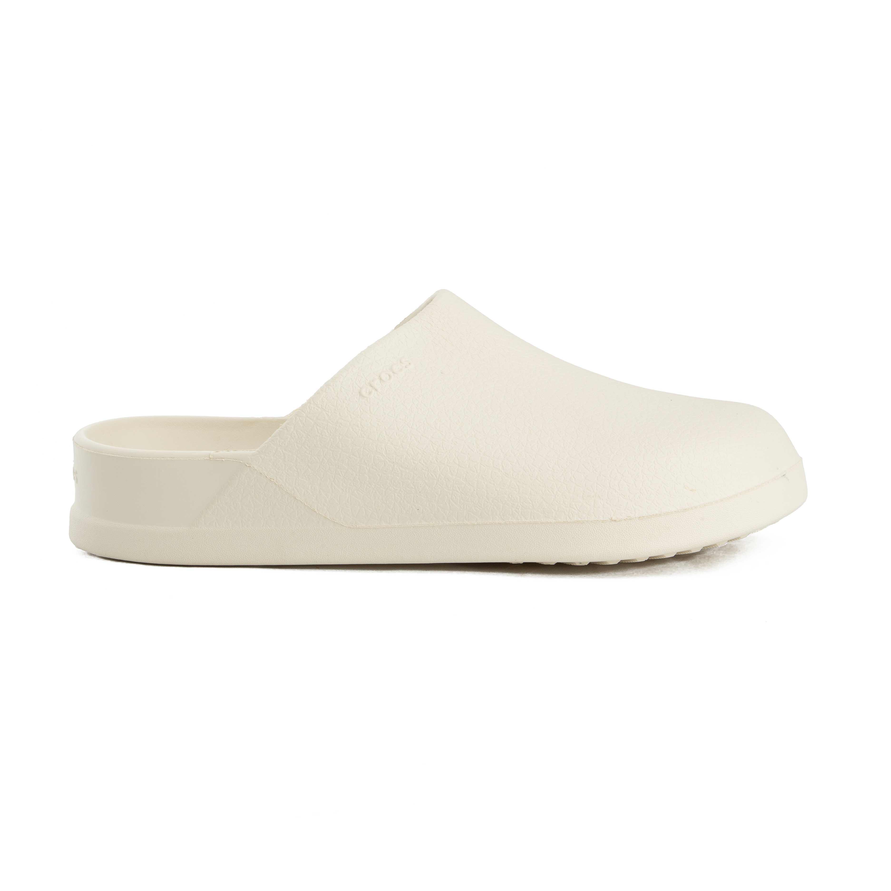 This is a pair of closed-toe, unvented clogs from the Crocs brand, presented in a soft, off-white color. 