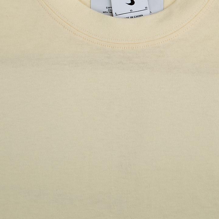 A plain cream-colored Nike t-shirt with a minimalist, clean design.