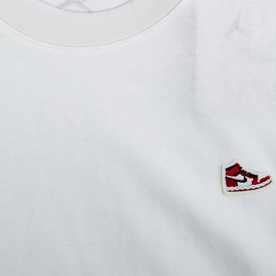 A white Jordan Flight Heritage T-shirt with a small embroidered winged shoe logo on the chest.