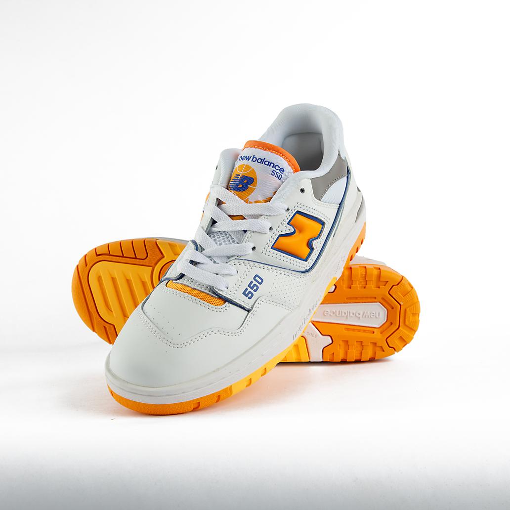 New Balance 550 sneakers in white with orange and gray details. A retro low-top shoe suitable for men and women.