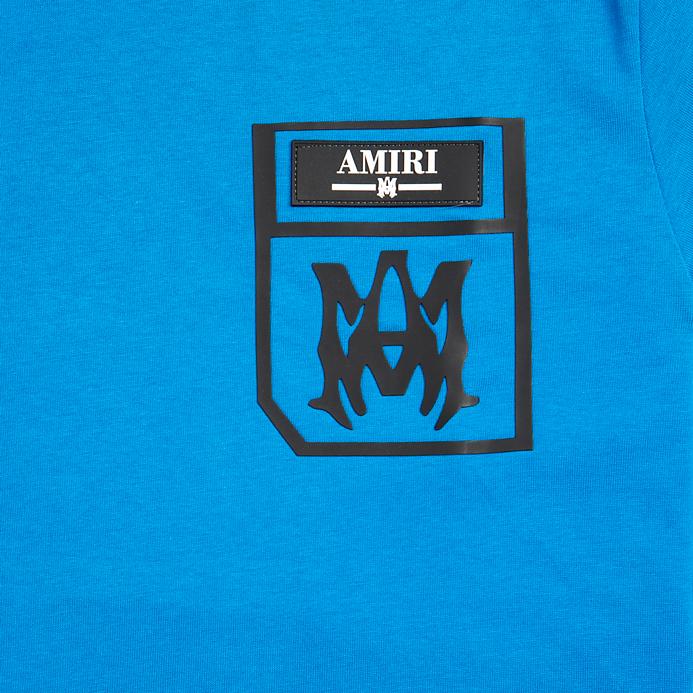 Bright blue Amiri unisex t-shirt with a black printed pocket logo featuring the AMIRI text and M monogram on the chest.