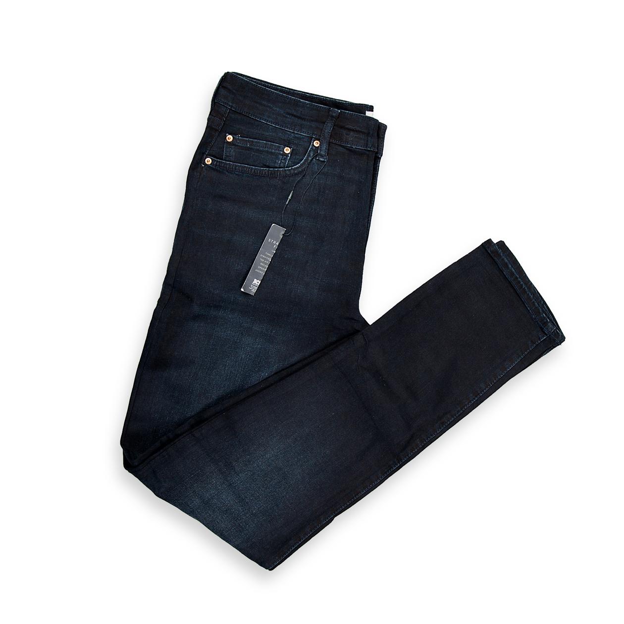 A foundational piece for any wardrobe, this is a timeless pair of men's jeans in a very dark, rich indigo wash. The wash is deep and consistent, suggesting a dressier, more refined aesthetic compared to a highly distressed or faded pair.