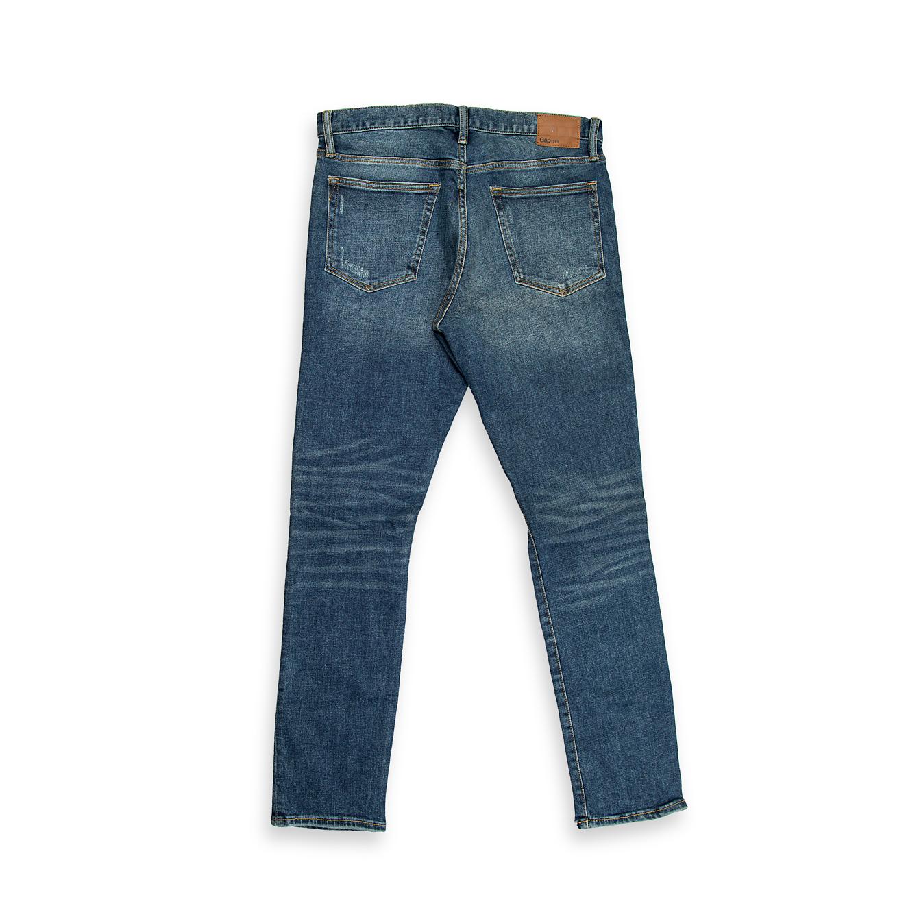These are a pair of slim-tapered fit denim jeans in a deep, vintage-inspired indigo blue wash. The wash features significant fading and whiskering across the front, creating a naturally aged appearance.