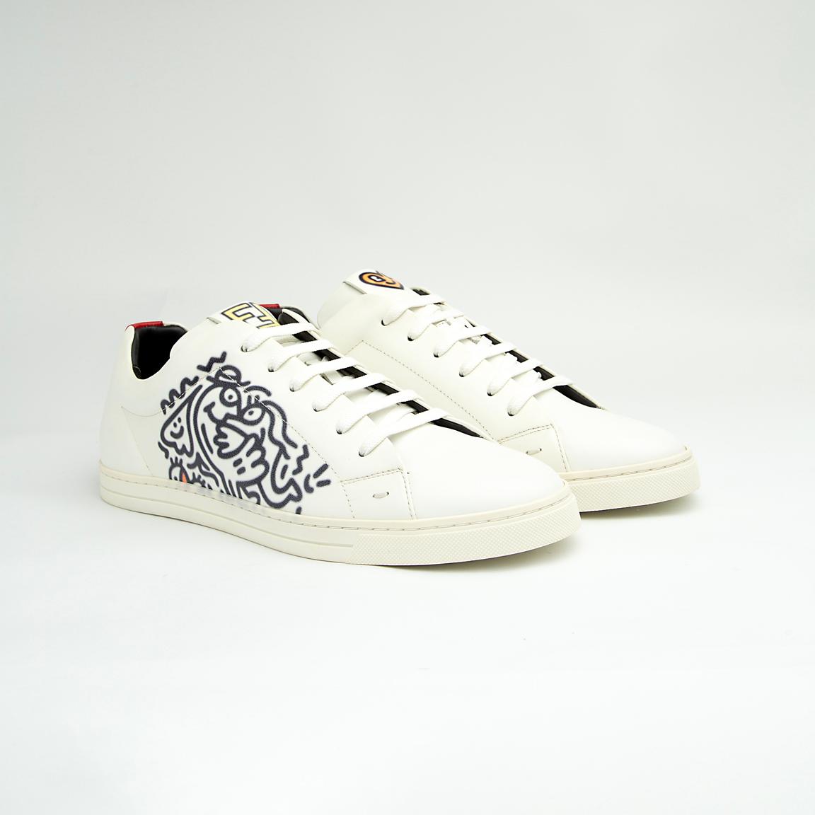 The White Tiger Skate Low is a clean, modern, low-top trainer with a luxury streetwear edge. It is crafted from smooth, premium white leather and features a distinctive black and white graphic drawing on the side panel, resembling a stylized tiger or abstract artwork.