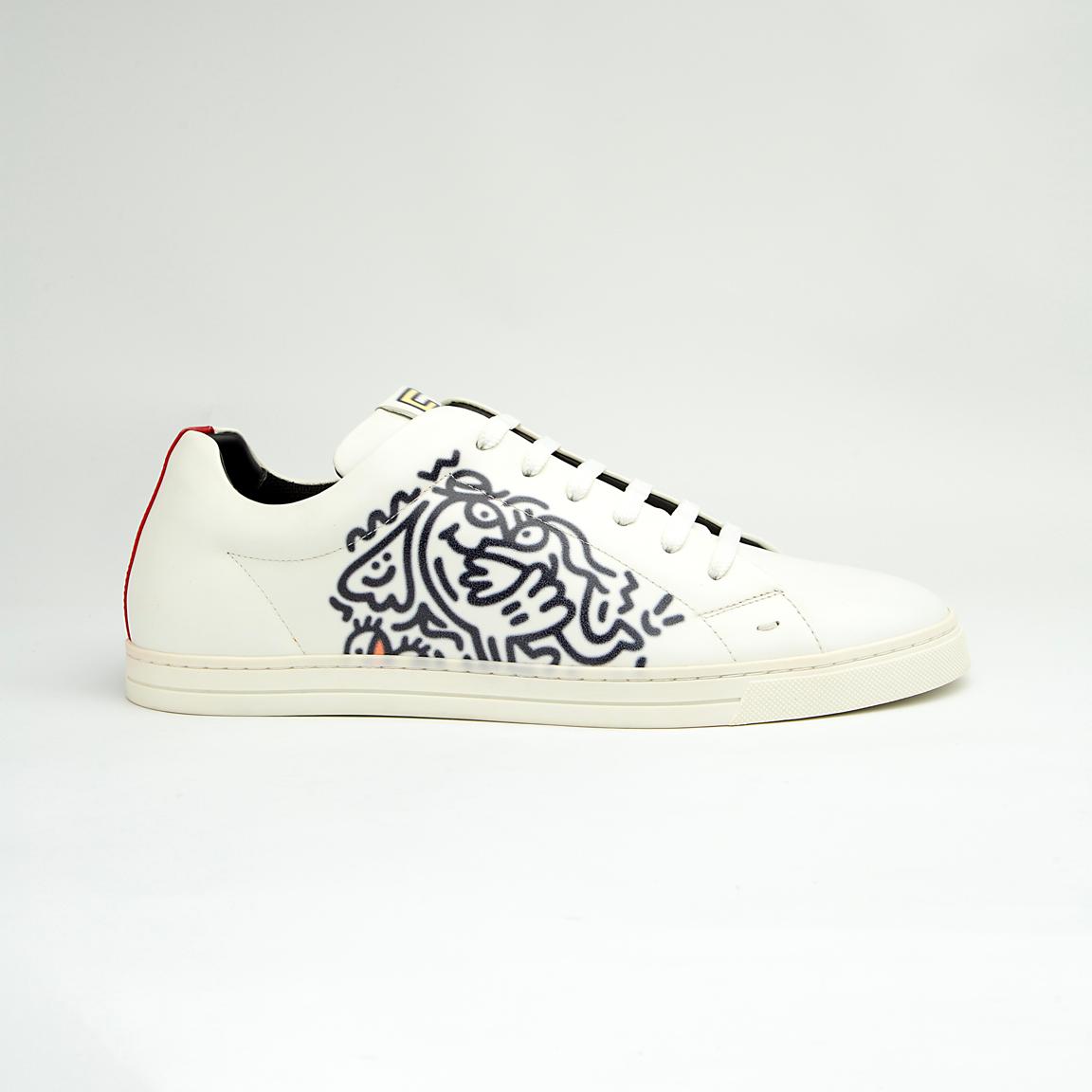 The White Tiger Skate Low is a clean, modern, low-top trainer with a luxury streetwear edge. It is crafted from smooth, premium white leather and features a distinctive black and white graphic drawing on the side panel, resembling a stylized tiger or abstract artwork.