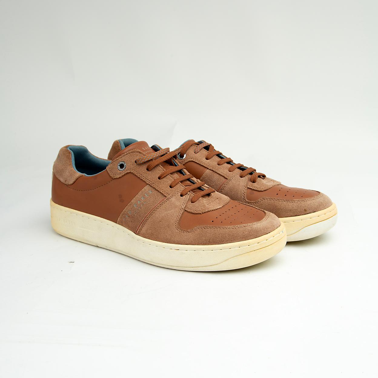 These versatile sneakers are crafted from a sophisticated mix of materials, featuring smooth brown leather panels complemented by textural suede accents in a matching tonal palette.