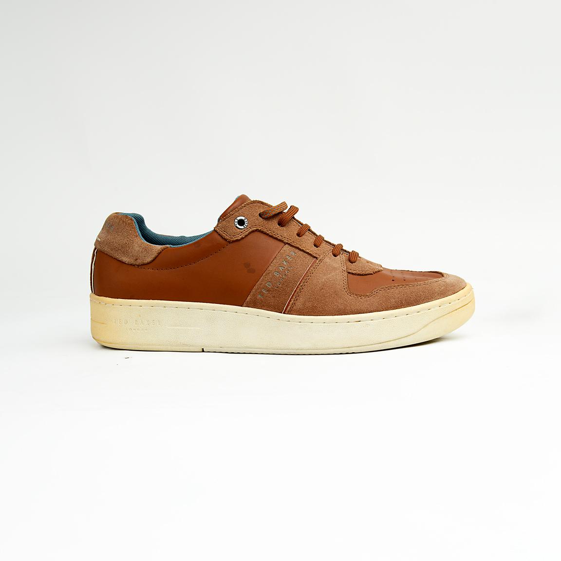 These versatile sneakers are crafted from a sophisticated mix of materials, featuring smooth brown leather panels complemented by textural suede accents in a matching tonal palette.