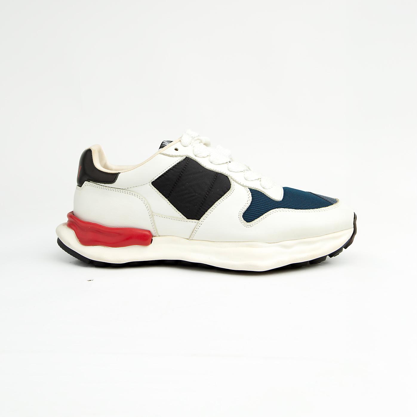 This bold sneaker features sophisticated color blocking with a base of pristine white leather, accented by rich navy blue mesh on the toe box and side panels, and black suede/nubuck near the laces.