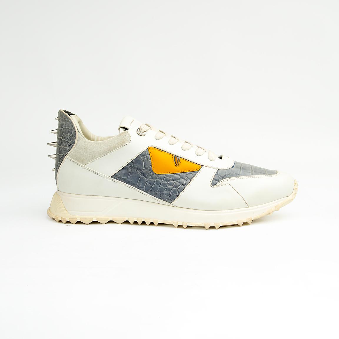 Crafted from premium leather, it features contrasting grey crocodile-embossed leather panels and a striking yellow-and-black triangular appliqué, reminiscent of a watchful eye.