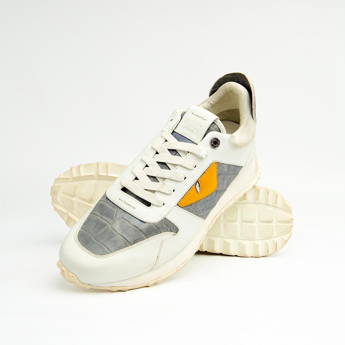 Crafted from premium leather, it features contrasting grey crocodile-embossed leather panels and a striking yellow-and-black triangular appliqué, reminiscent of a watchful eye.