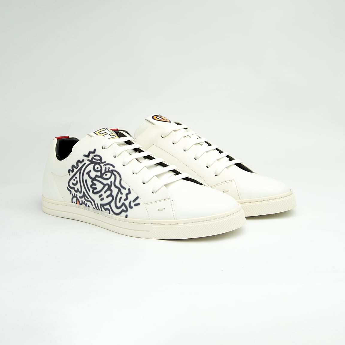 The White Tiger Skate Low is a clean, modern, low-top trainer with a luxury streetwear edge. It is crafted from smooth, premium white leather and features a distinctive black and white graphic drawing on the side panel, resembling a stylized tiger or abstract artwork.